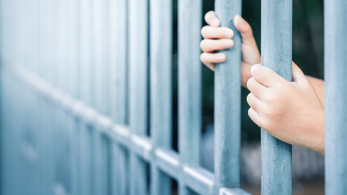 A file picture of a child's hands behind bars. File picture