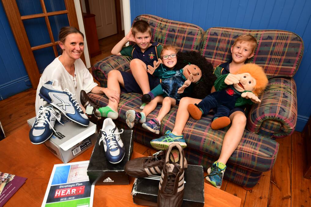 SHOES FOR BETTER HEARING: Priya McDonald trying the Hear Our Heart fundraiser football boots on her son Oliver, next to Annie and Flynn. Photo: BELINDA SOOLE