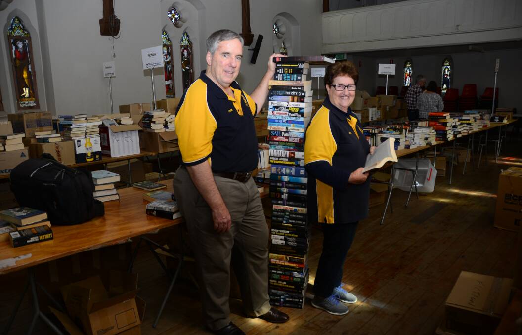 TALL ORDER: Rotary Club of Dubbo Macquarie charter members Peter Bartley and Lorna Breeze help arrange 15,000 books on sale from 8am Saturday.   