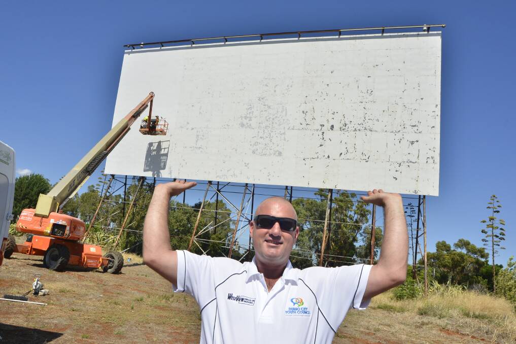 Powering on: Dubbo Regional Council youth development officer Jason Yelverton lifts up the drive-in project as the screen receives a fresh coat of paint. Photo: BELINDA SOOLE