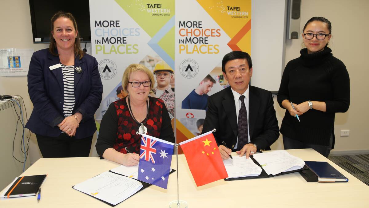 SIGNED AND SEALED: TAFE Western teacher Susan Bird watches as institute director Kate Baxter signs the co-operation agreement with Shanghai AXGZ Education Training Co Ltd chairman and chief executive officer Lawrence Feng beside company representative Shirley Feng.Photo: Contributed
 