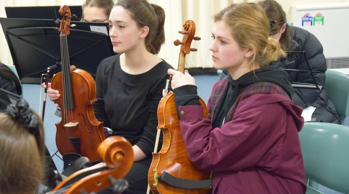 MUSICAL MOMENT: Emma Newby and Cassandra Doyle listen intently during a previous visit to Dubbo by the Sydney Youth Orchestras.  Photo: Contributed
