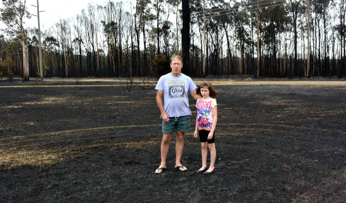 IN THE PATH OF FIRE: Robert Dobing with nine-year daughter Lily on Northcote Street, where homes came under threat as the Kurri Kurri fire raged. Picture: Brodie Owen