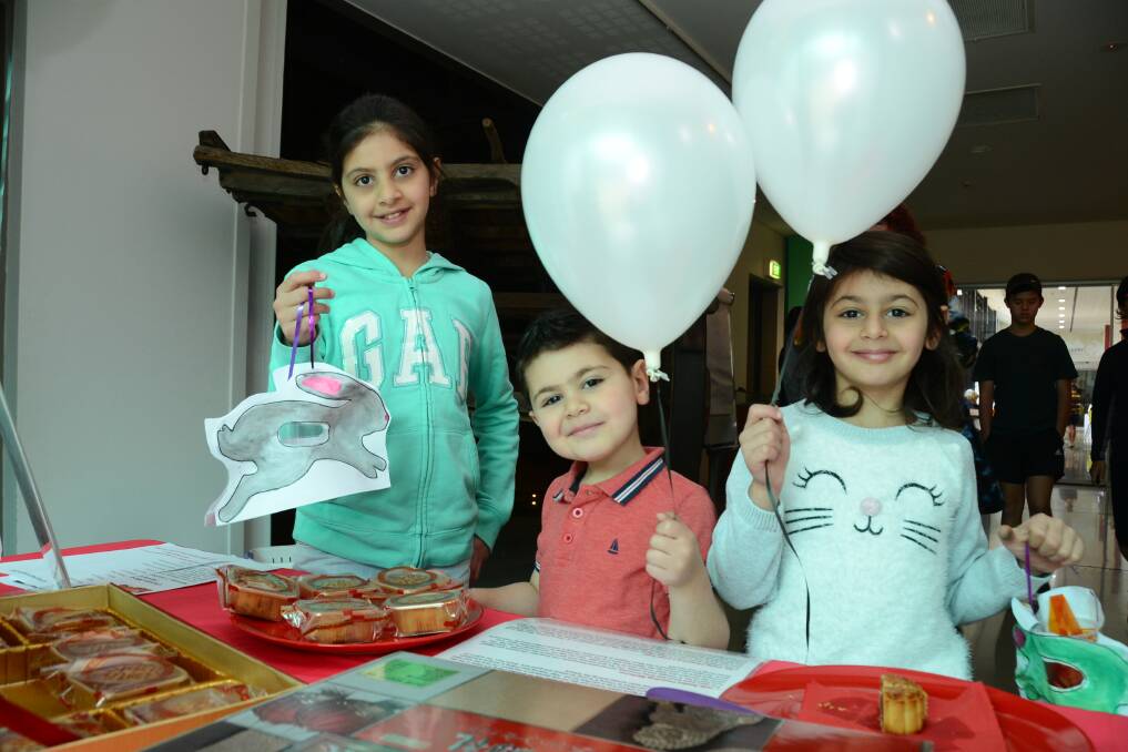 Learning: Rabab Helal, 10, Ammar Helal, 4 and Lara Helal, 7, hold their bunny lanterns and balloons and check out mooncakes at the Western Plains Cultural Centre's Chinese Mid-Autumn Festival celebration. Photo: BELINDA SOOLE