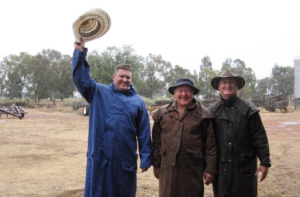 Ray White Rural's Daniel Armitage (left) and Brian McAneney (right), and farmer Cal Hawkins smile in the rain on Sunday. Photo: FAYE WHEELER