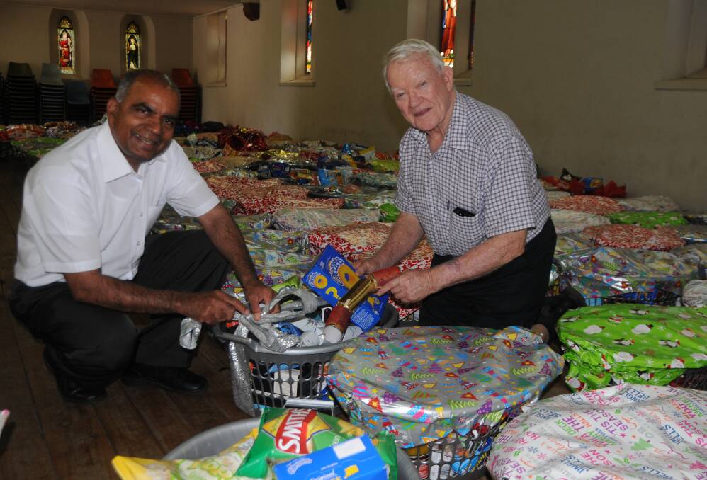 Spirit of giving: Fr Joshy Kaithakulangara, assistant parish priest at St Brigid's, and Christmas hamper appeal coordinator Dan Sullivan wrap the gifts. Photo: FAYE WHEELER