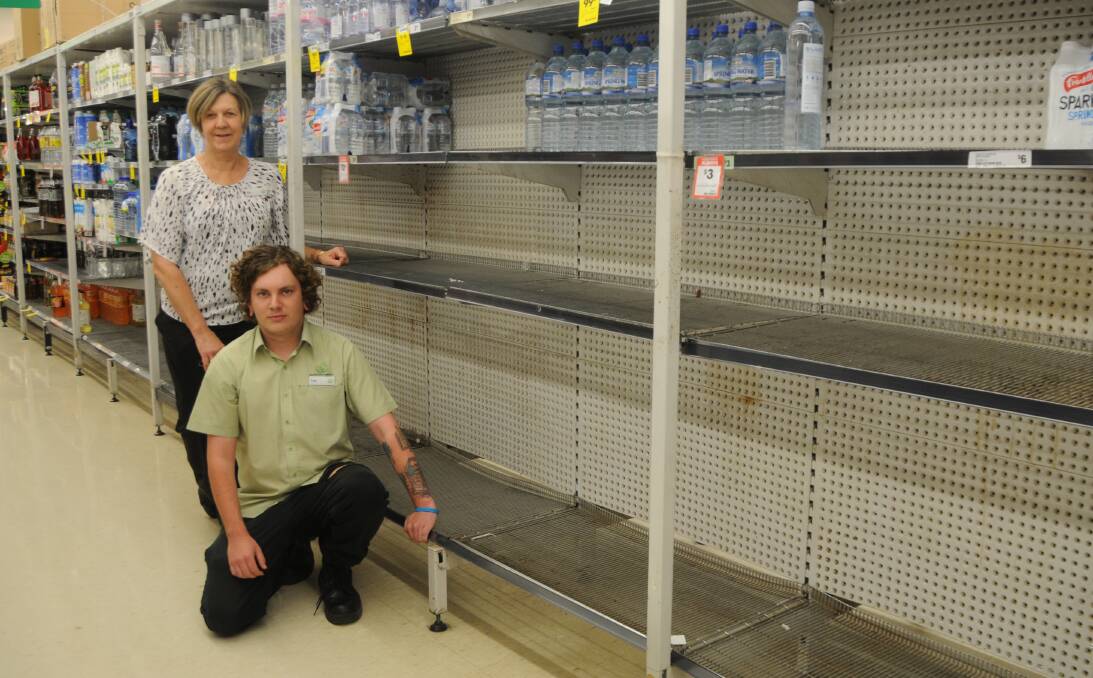 SELLING OUT: Woolworths Riverdale store manager Gai Hicks and employee Tom Hill with shelves that are usually full of bottled water. A delivery of bottled water is due in-store on Tuesday. Photo: JENNIFER HOAR