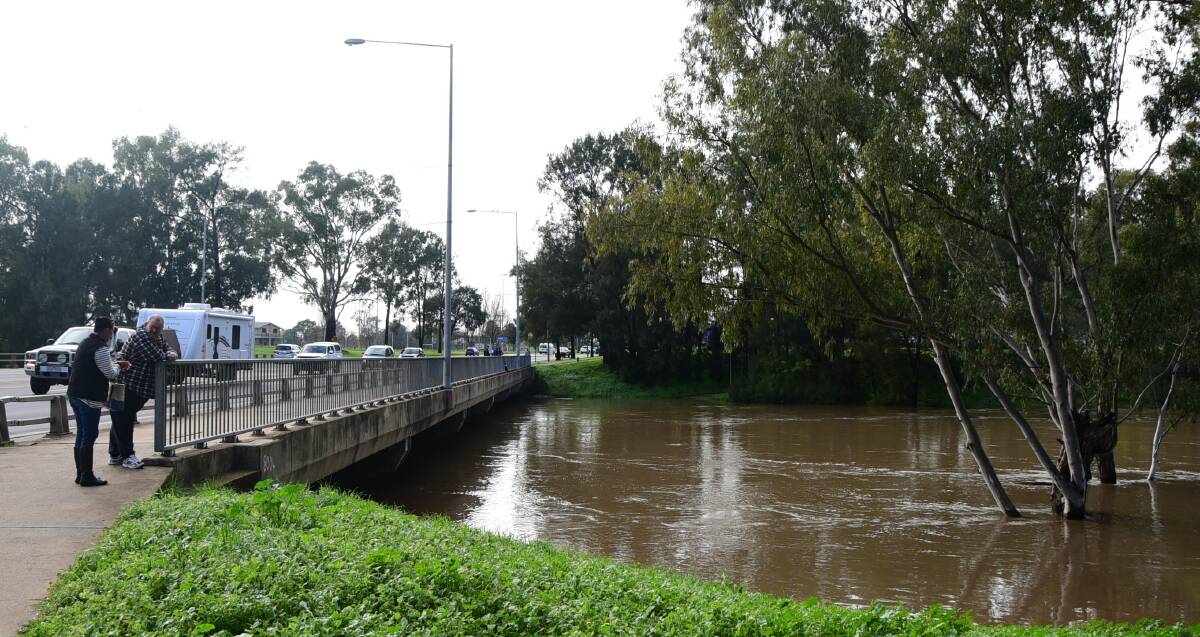 Inundated: Curious onlookers marvel at the height of the Macquarie River under the Emile Serisier Bridge on Thursday morning. Photo: BELINDA SOOLE