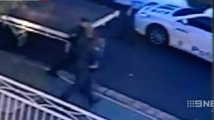 The two-year-old is whisked away by police while the truck driver is arrested. Photo: Nine News