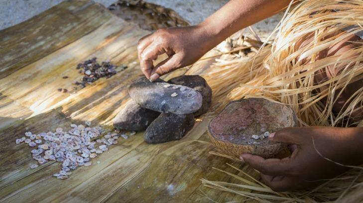 A woman makes shell money, whittling down shells into small shapes.  Photo: iStock