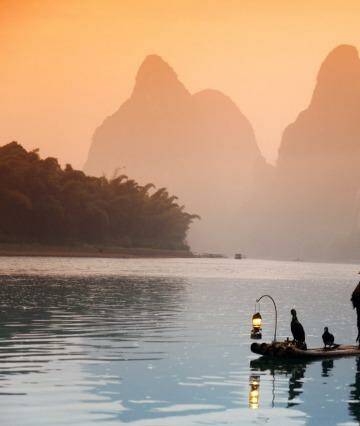 A man fishes with cormorants on a river.  Photo: 123rf.com