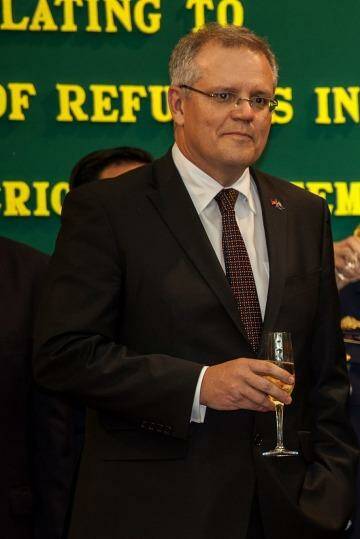 Australian Immigration Minister Scott Morrison and Cambodian Interior Minister Sar Kheng hold a flute of champagne after signing a deal to resettle refugees from Australia to Cambodia. Photo: Omar Havana