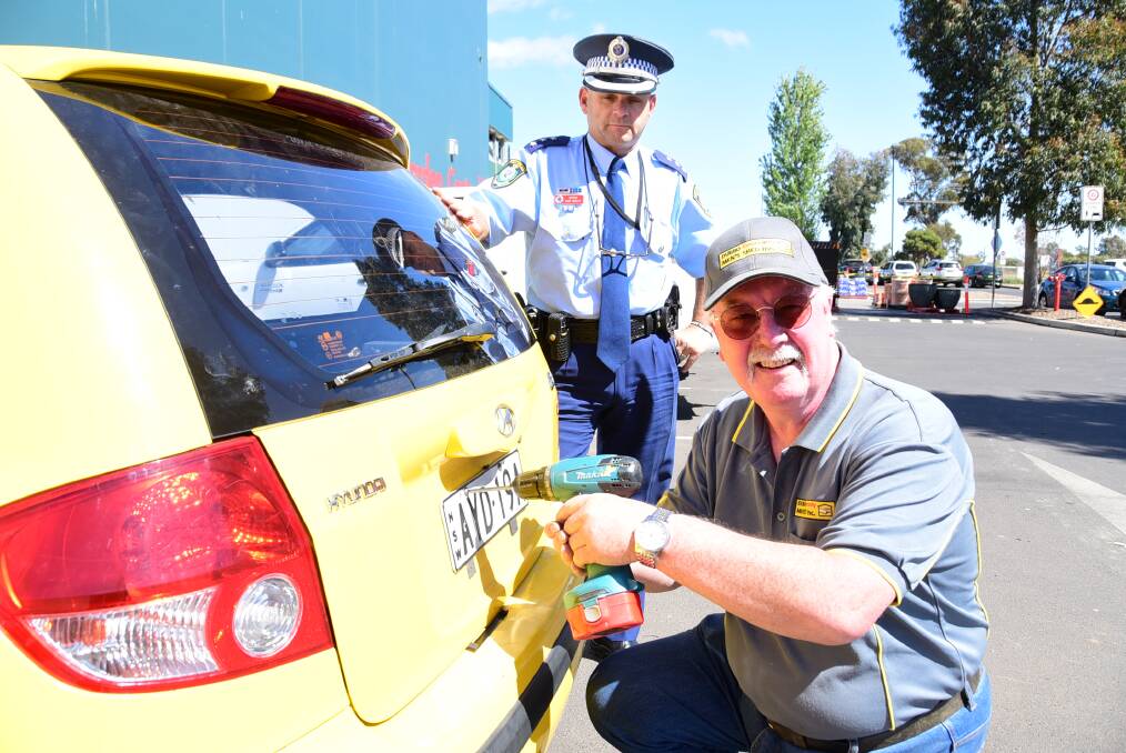 Orana LAC inspector Dan Skelly and Dubbo Community Men's Shed secretary John Gibson fit Lorry Weldon's car with anti-tamper screws as part of Saturday's Community Engagement Day. Photo: CHERYL BURKE