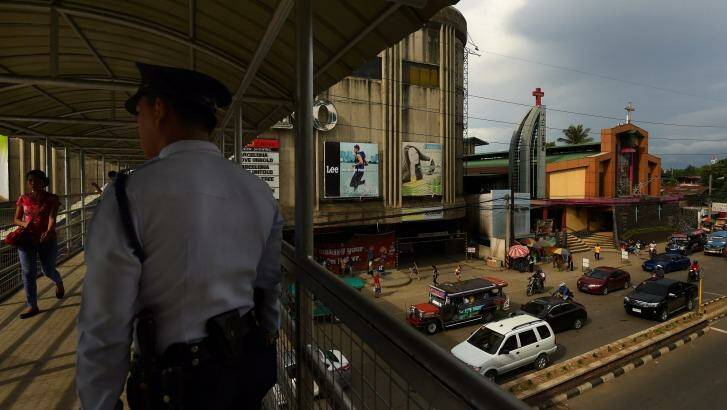 A police officer stands on the overpass connecting two malls in Cagayan De Oro where two of Peter Scully's victims were allegedly groomed by his girlfriend.  Photo: Kate Geraghty