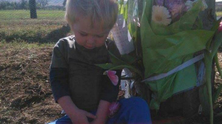 Declan Lambkin besides flowers at the spot where his father Christopher died on the Golden Highway. Photo: Supplied