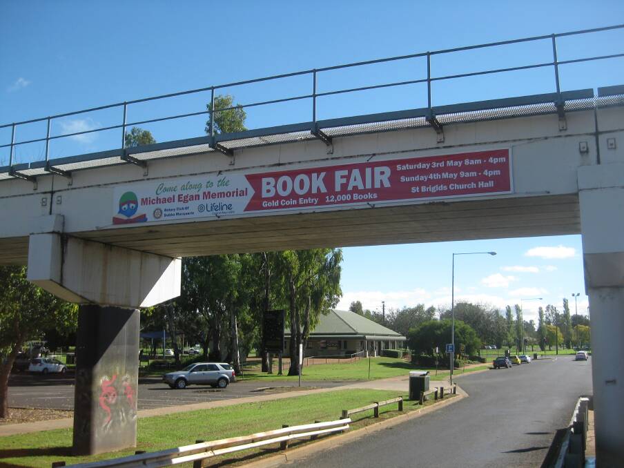 A banner displayed from the railway bridge in Macquarie Street promoting a community fundraiser earlier this year before the Australian Rail Track Corporation banned the practice this week. 										       Photo: contributed