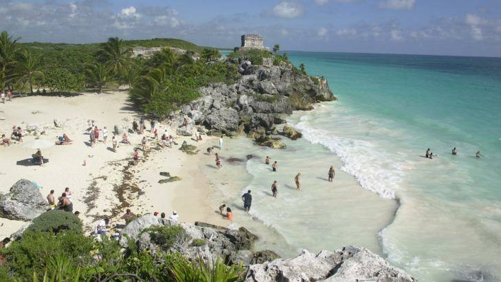 Tourists enjoy the beach near the Mayan ruins of El Castillo in Mexico.

