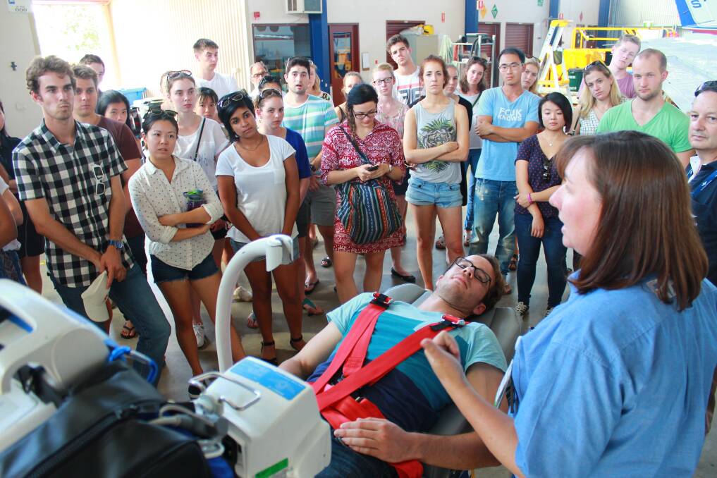 University of Sydney student Kieran Muir volunteered to be on the stretcher, with RFDS Flight Nurse Keryn Bolte showing the group how a patient is loaded into the plane. Photo supplied.