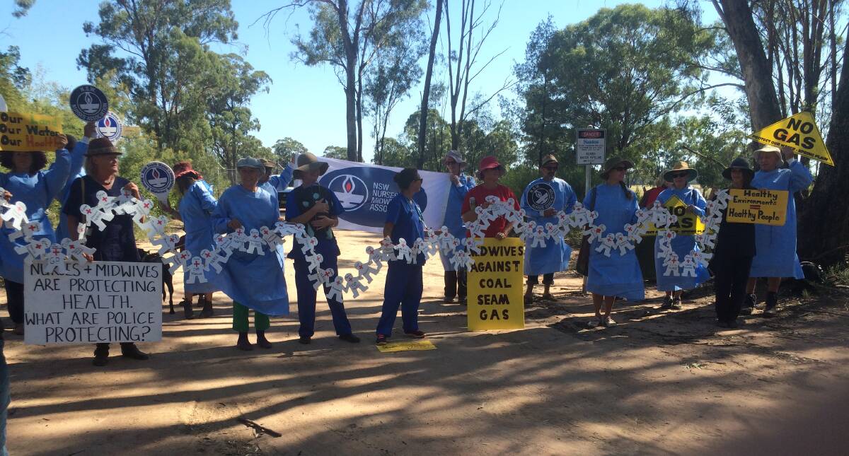 Nurses and midwives dressed in scrubs hold signs during a peaceful protest in the Pilliga forest on Thursday. The cardboard cut-outs represent other health workers who were unable to leave their patients to participate in the protest.					  Photo: SUPPLIED