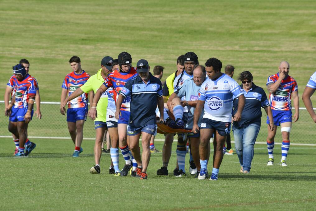 Players and staff carry an injured Dylan Hill from the field on Sunday.  
Photo: BELINDA SOOLE