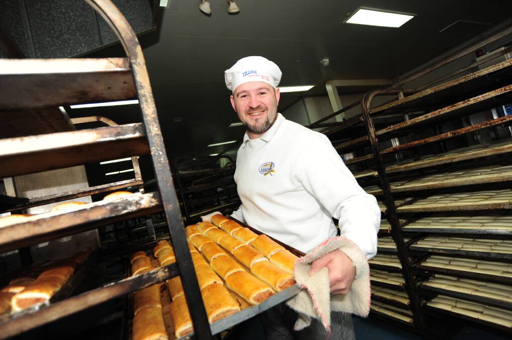 Director of Pies and Pastries at Earlyrise Baking John Stevenson taking freshly baked sausage rolls out of the oven.
