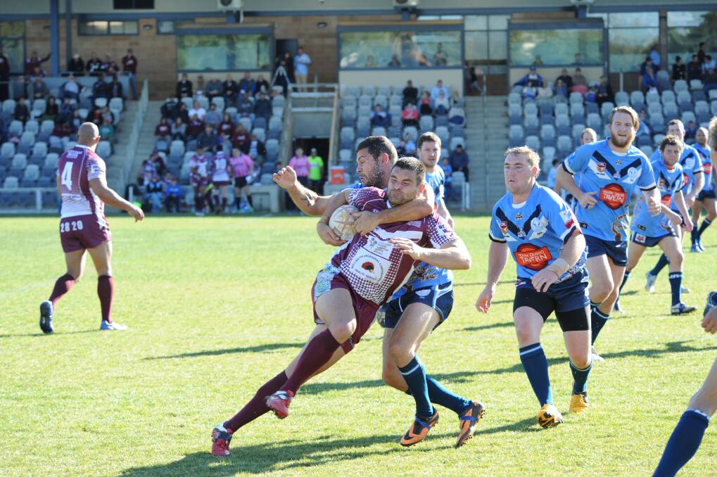 Macquarie s Chris Daley wraps up Wellington s Robbie Donn during yesterday s match.	Photo: LOUISE DONGES