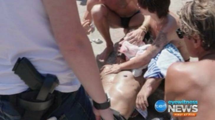 Beachgoers hold a towel to the head of a man who was attacked at Bondi on Thursday. Photo: Ten News