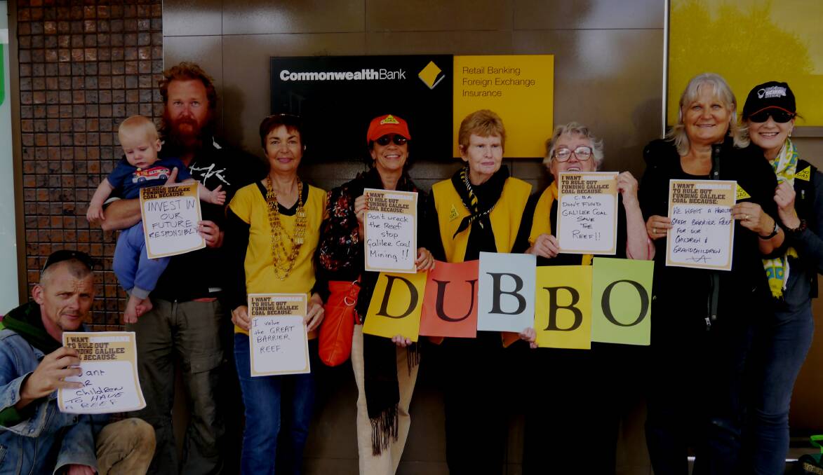 David Mould, Peter Duggan holding Flynn, Margaret McDonald, Lyn Jablonski, Margaret Evans, Shirley Colless, Bev Hamilton and Sally Forsstrom holding protest signs outside the Commonwealth Bank. 
PHOTO SUPPLIED