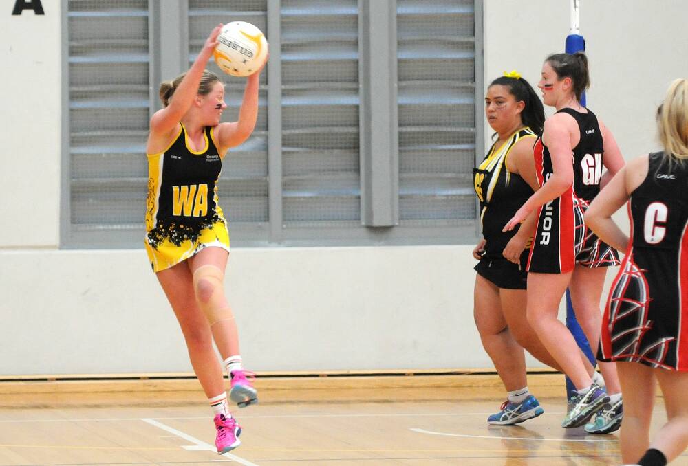 Chloe Riley keeps the ball away from her Dubbo rivals during Thursday's Astley Cup netball match. Photo: STEVE GOSCH