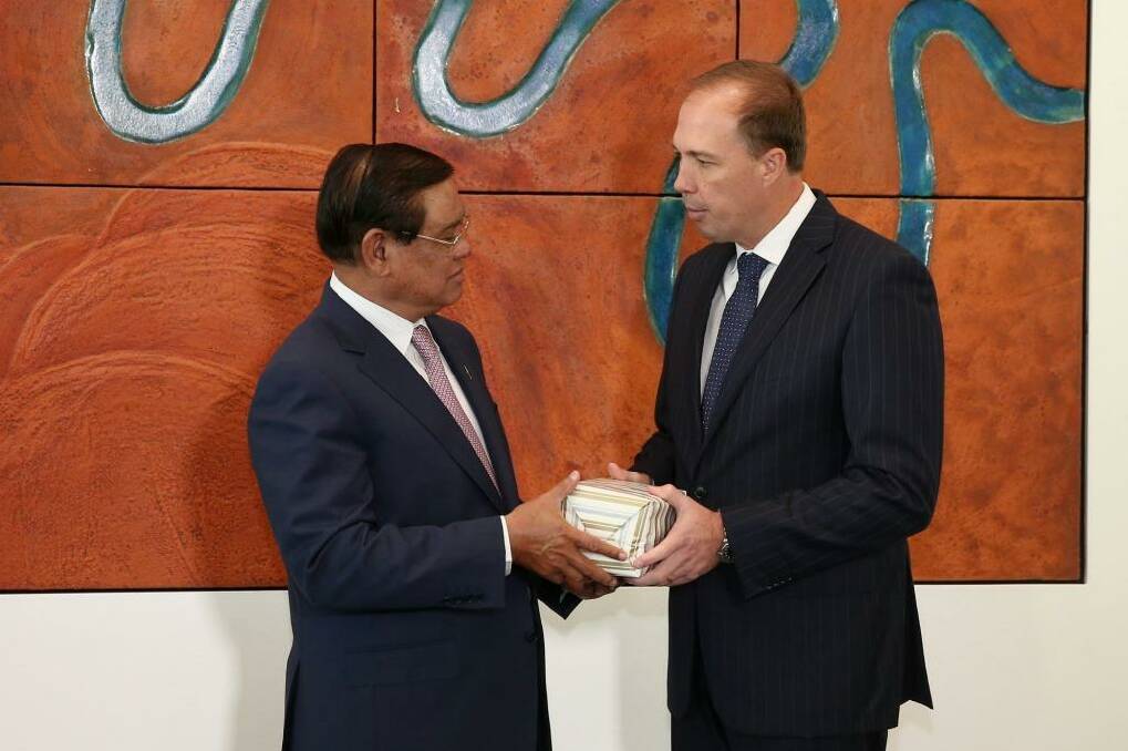 Immigration Minister Peter Dutton gives a present to Cambodian Deputy Prime Minister and Minister of the Interior Sar Kheng, during a signing of a memorandum of understanding. Photo: Alex Ellinghausen