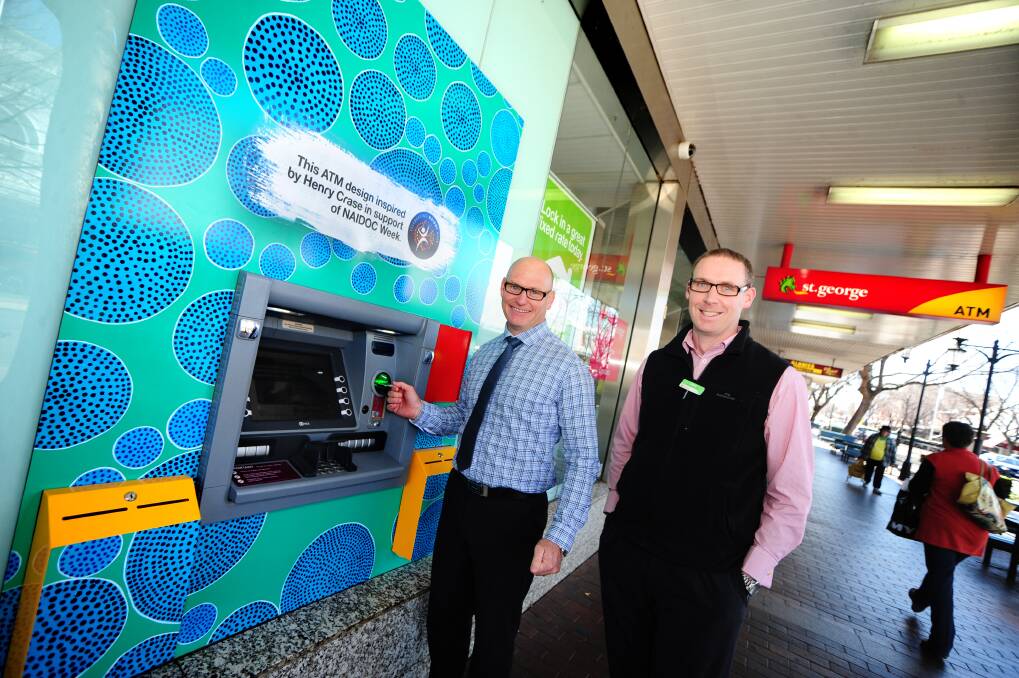 Drawing money out of the St George ATM on Macquarie Street are regional executive for St George Dan Pobje and St George digital ambassador Adam Wells. 
Photo: LOUISE DONGES