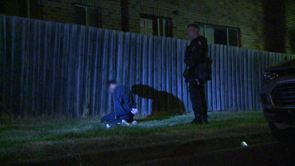 One man detained by police kneels on the ground as a raid is carried out.  Photo: Reuters/Australian Federal Police