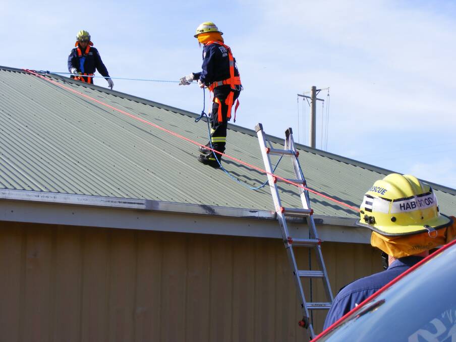 Firefighter Scott Habgood watches from the ground as fellow firefighters scale the roof of a house.