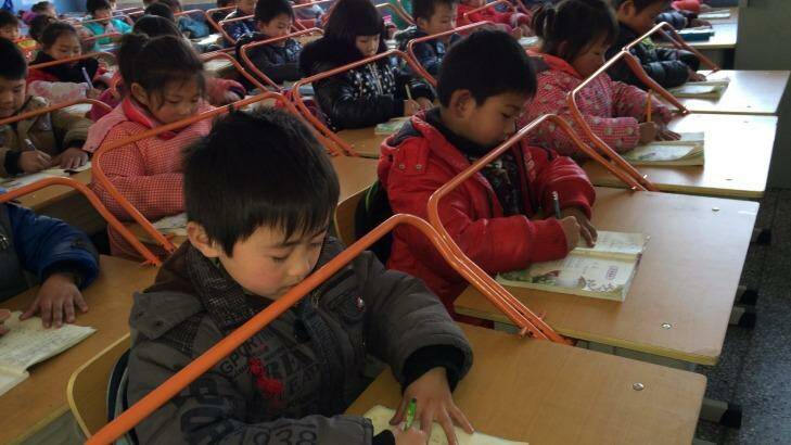 Chinese children read books with special desks equipped with iron bars to help them protect their eyesight. Photo: ChinaFotoPress