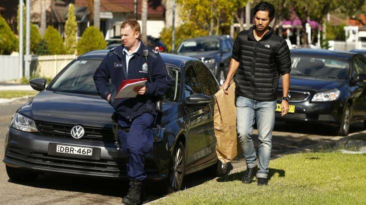 Police carry a bag of evidence after raiding a home in Punchbowl Photo: Daniel Munoz