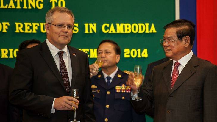 Australian Immigration Minister Scott Morrison and Cambodian Interior Minister Sar Kheng hold a flute of champagne after signing a deal to resettle refugees from Australia to Cambodia. Photo: Omar Havana