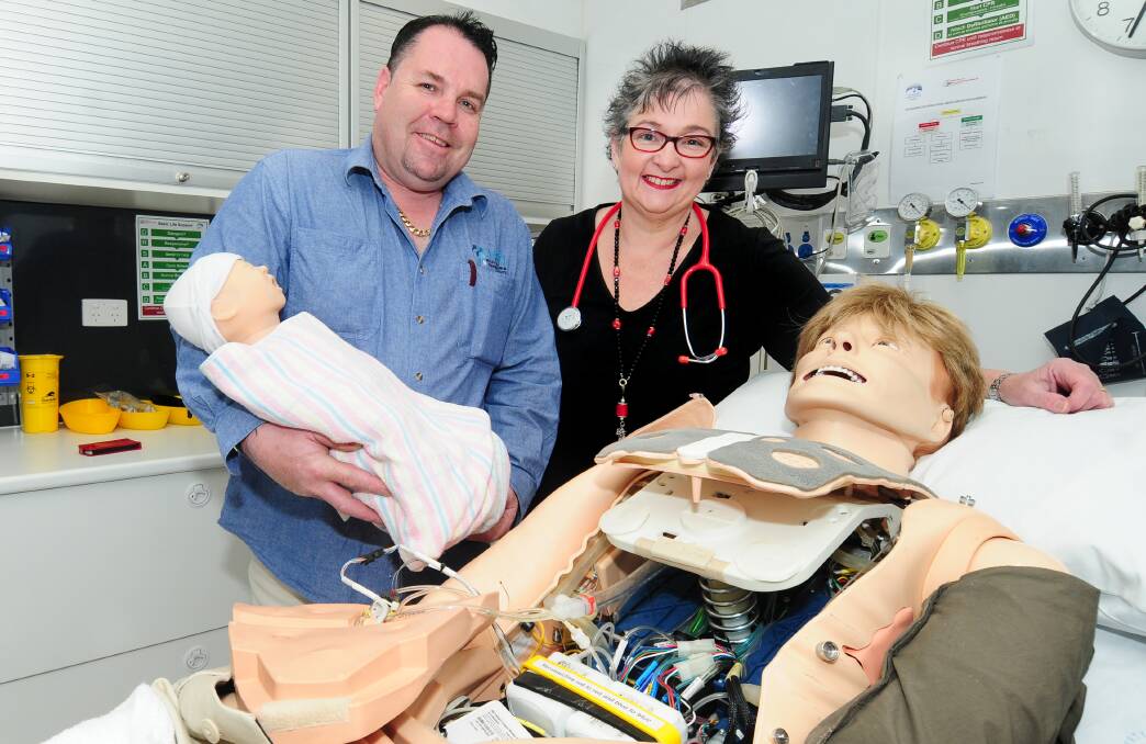 Driver Brendan Glass and HETI manager Tod Adams show off the inner workings of George, a high-tech mannequin designed to teach life-saving skills to medical professionals. Mr Glass also displays a sim baby. 							         Photo: LOUISE DONGES.