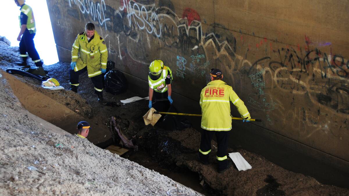 Fire and Rescue NSW work to clear the oil sludge under the Emile Serisier Bridge. Photo: Hannah Soole