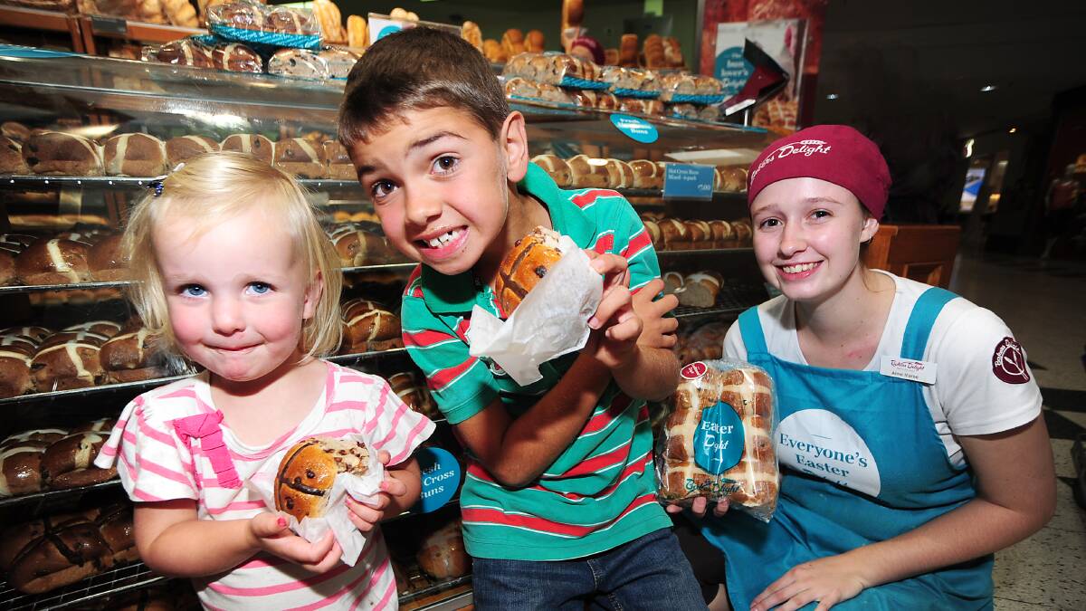 Cousins Ayla and Wade Brown taste-test some of the fresh hot cross buns with Anne Maree Ferguson from Bakers Delight.  Photo: BELINDA SOOLE

