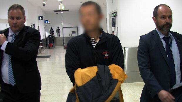Hongchi Xiao, escorted by police at Sydney airport, was taken to Kogarah police station.  Photo: NSW Police
