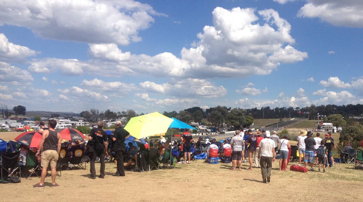 THE DISTANT RUMBLE: Racing spectators stand still to see the cars race appear over the crest.
Photo: JAMES LISLE.