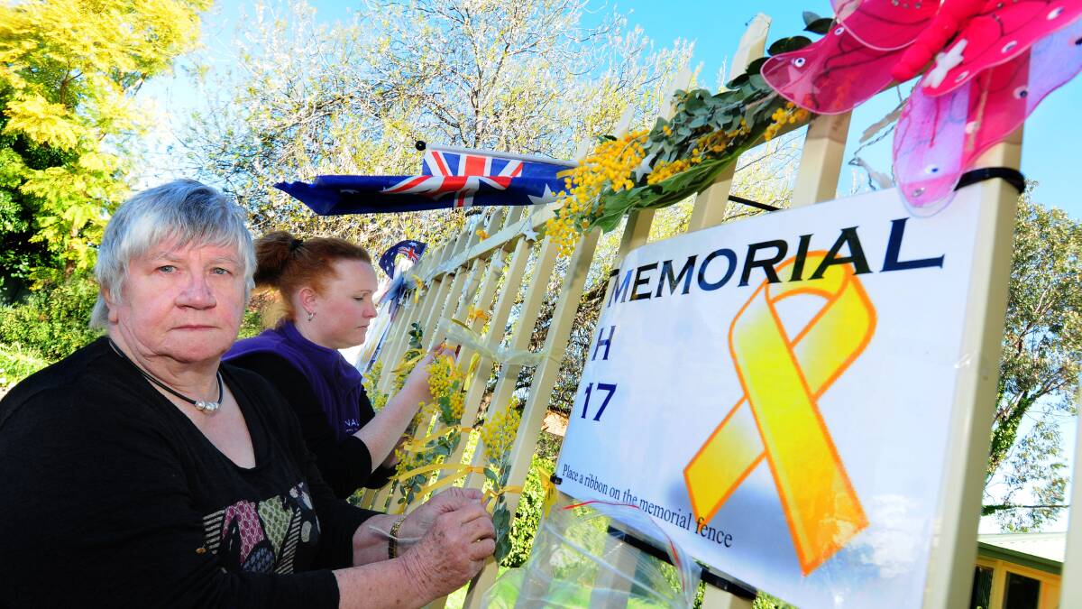 Trudy Hanson manager and Natasha Ireland education and promotion both of NALAG tie yellow ribbon of the fence of the NALAG MH-17 Memorial
	 Photo: LOUISE DONGES