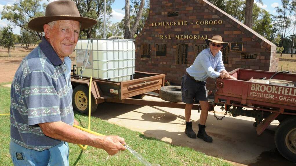 Eumungerie residents Les Brookfield and Leo de Kroo use their own water to care for the grounds of the Eumungerie cenotaph, carried by their vehicles. Photo: BELINDA SOOLE
