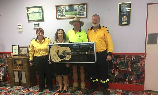 LUCKY WINNERS: Wongarbon RFS' Carole Bayley and Brett McCarthy with the new owners of the Red Hot Summer Tour guitar. Photo: CONTRIBUTED