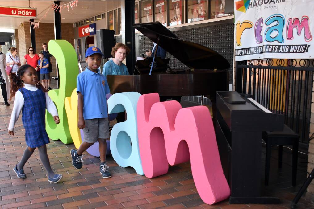 MUSIC IN THE AIR: Samara and Alex Faponle watching Michael Noonan play one of the DREAM Festival pianos before they took their own turn. Photo: BELINDA SOOLE