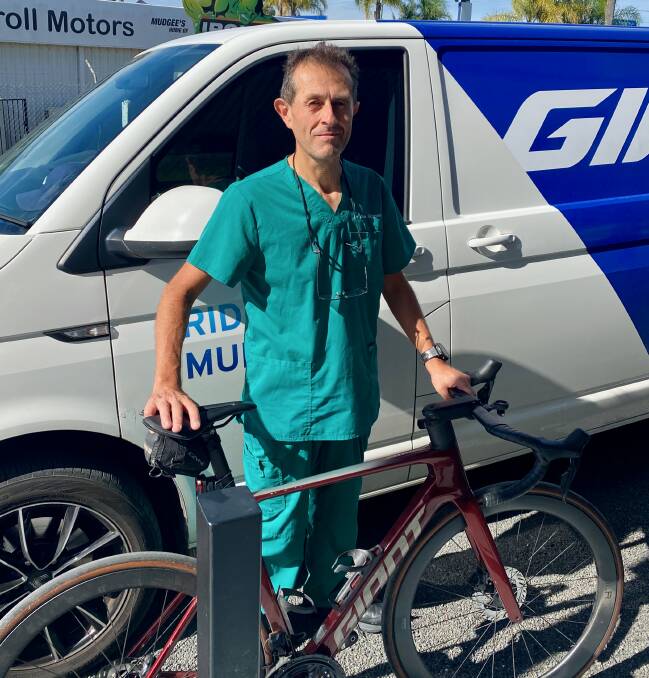 Dr Alex Ghanem in his scrubs standing next to his bike. Photo: Supplied