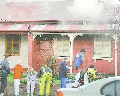 FIRE HORROR: Neighbours and fire officers assist victims after Sunday’s fire at a Cobra Street home (above photo courtesy FRANK REDWARD).