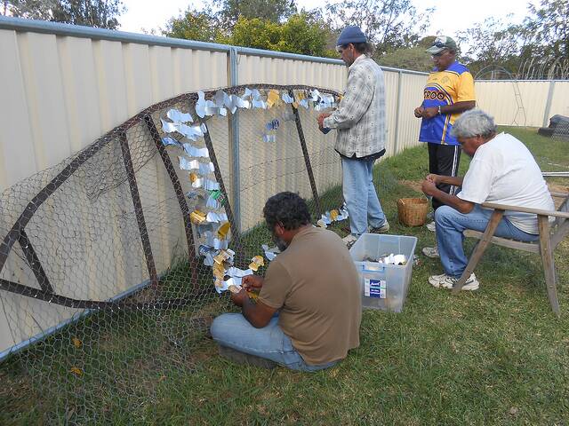 Community members add scales to the fish.