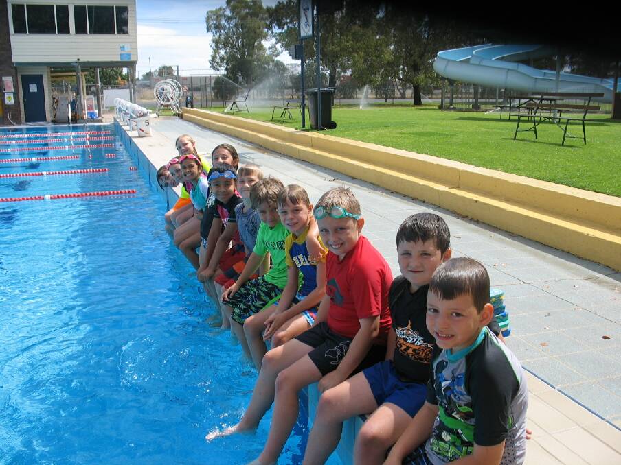 Children waiting on the side of the pool ready for swimming.