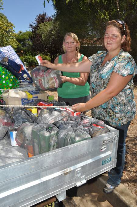 Michelle Kent gives Kristen Campbell some items she has donated for the victims of the Coonabarrabran fires. 
	Photo: LISA MINNER